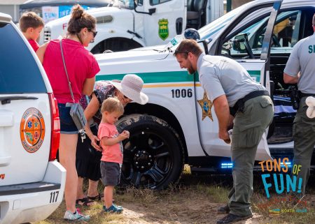 sheriff with young kids touch a truck north river ranch